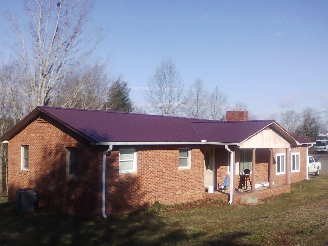 Burgundy metal roof on a brick ranch home with a new addition in House Springs