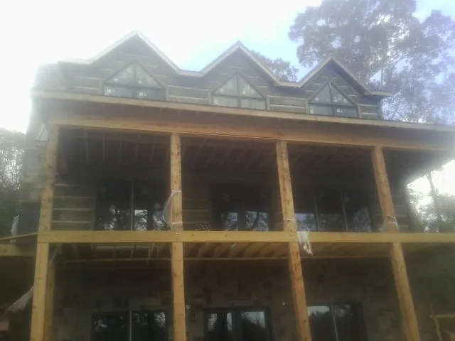 Dormers and porch framing on a large log home under construction — Roof Coating work by our crew in House Springs