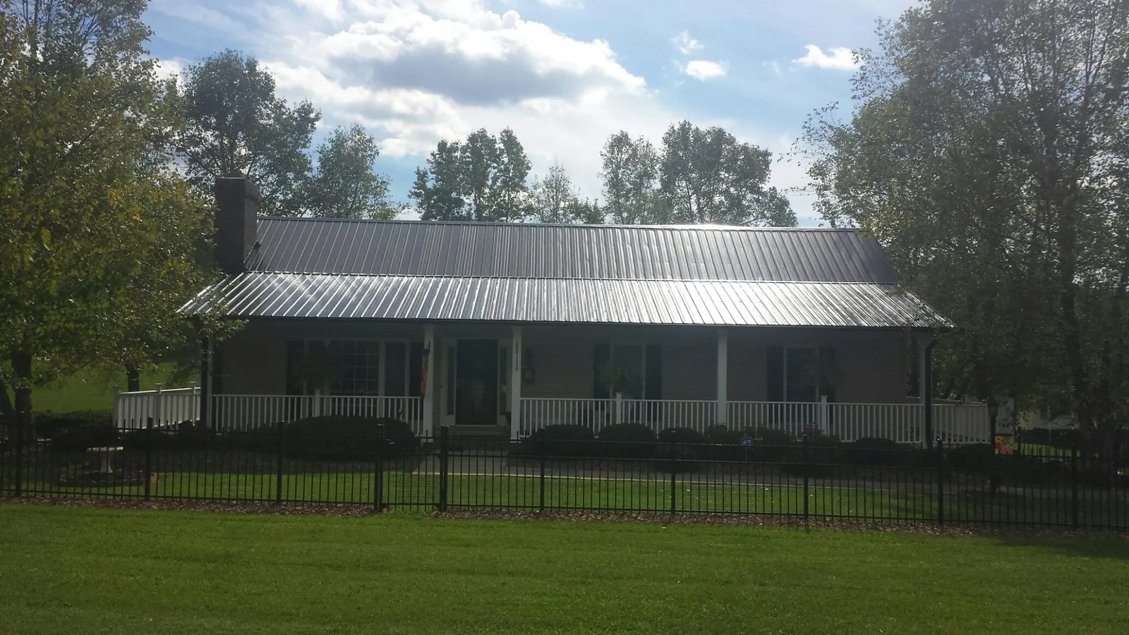 Gray metal roof on a brick ranch with a full width front porch — Gutter Guard Installation work by our crew in House Springs