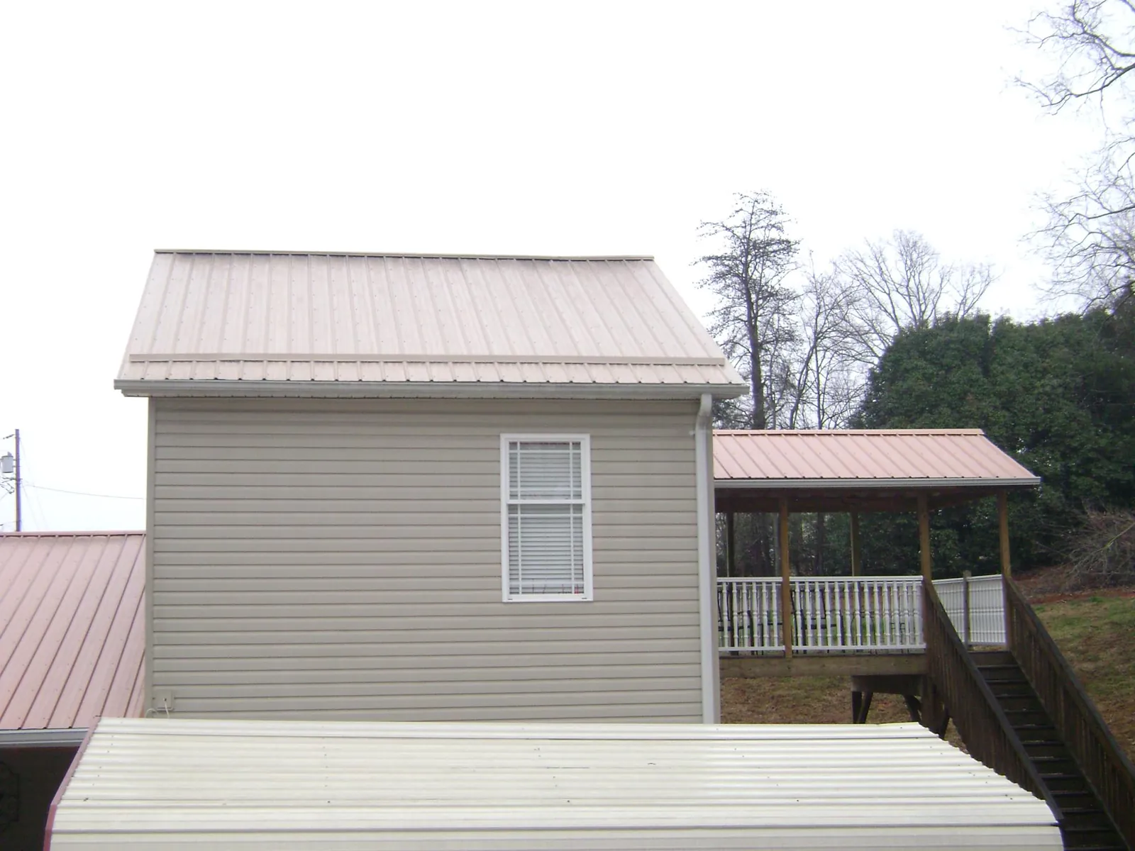 Tan metal roofs on a two story addition and attached porch, from a Roof Replacement job in House Springs