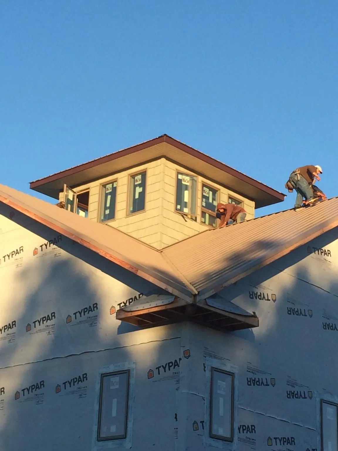 Roofers working around a rooftop cupola on a new metal roof at sunset — Roof Waterproofing in House Springs by Roofing Brothers